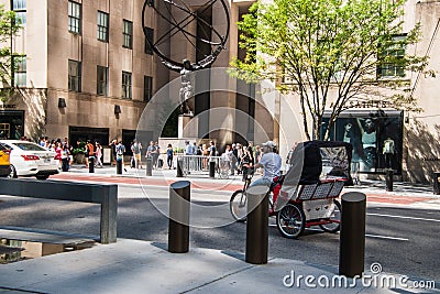 A pedicab is seen riding along an avenue in Manhattan in front of the Atlas statue at Rockefeller Plaza Editorial Stock Photo