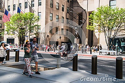 A pedicab is seen riding along an avenue in Manhattan in front of the Atlas statue at Rockefeller Plaza Editorial Stock Photo