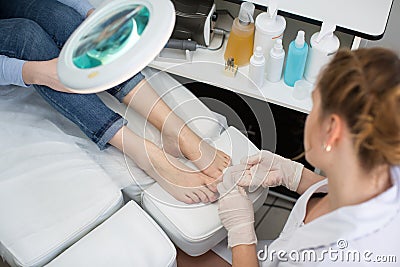 Pedicure dead skin remover foot rasp woman in nail salon. Application of the cream. Stock Photo