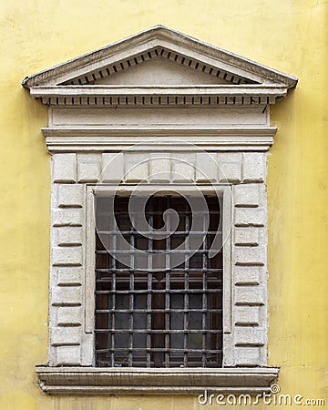 Pediment above a window of an ancient european house. Window with a wrought iron lattice. Stock Photo