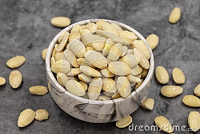 Peeled almond kernel on dark background. A bowl of almonds Stock Photo