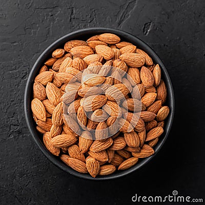 Peeled almonds in a bowl on a black textured background Stock Photo