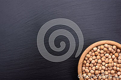 Peeled chickpeas lies in a wooden cup on a stony black board, black background, space for text Stock Photo