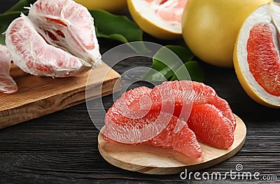 Peeled pomelo slices on black wooden table Stock Photo