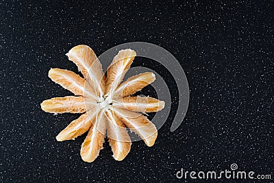 Peeled and sectioned fresh orange on a black cutting board Stock Photo