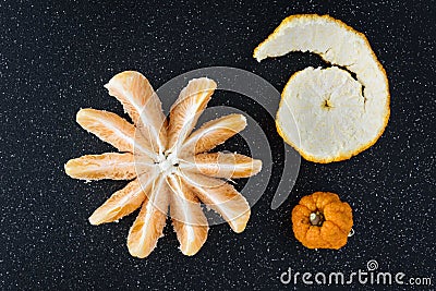 Peeled and sectioned fresh orange on a black cutting board Stock Photo