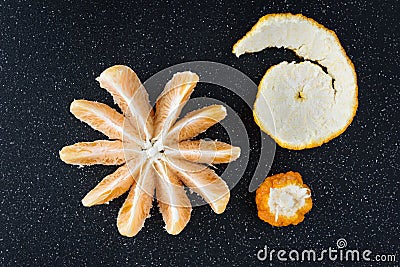 Peeled and sectioned fresh orange on a black cutting board Stock Photo