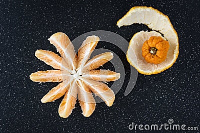 Peeled and sectioned fresh orange on a black cutting board Stock Photo