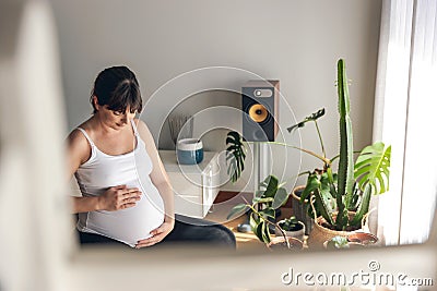 Pegnant woman at home feeling her baby Stock Photo