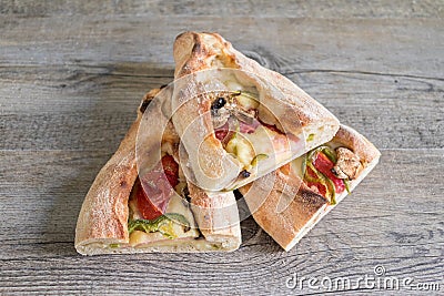 Peinirli - Greek open faced pizza with ham, cheese and vegetables, three half pieces on wooden kitchen surface Stock Photo