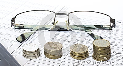 Pen on financial and accounting reports with coins stacks, glasses and calculator Stock Photo