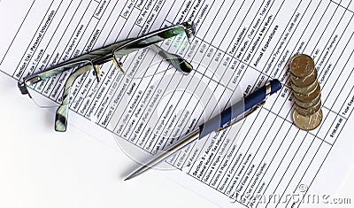 Pen on financial and accounting reports with coins stacks, glasses and calculator in background Stock Photo