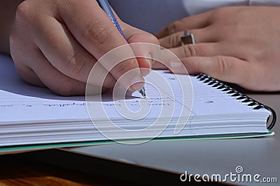 Pen in hand, woman writing in a spiral bound notebook Stock Photo