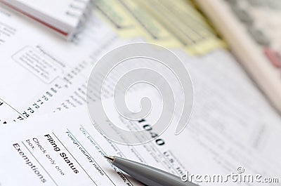 The pen, notebook, calculator, and dollar bills is lies on the tax form 1040 U.S. Individual Income Tax Return. The time to pay Editorial Stock Photo