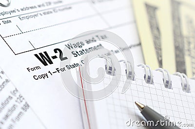 The pen, notebook and dollar bills is lies on the tax form W-2 Wage and Tax Statement. The time to pay taxes Editorial Stock Photo