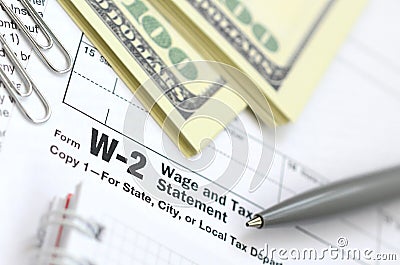 The pen, notebook and dollar bills is lies on the tax form W-2 Wage and Tax Statement. The time to pay taxes Editorial Stock Photo