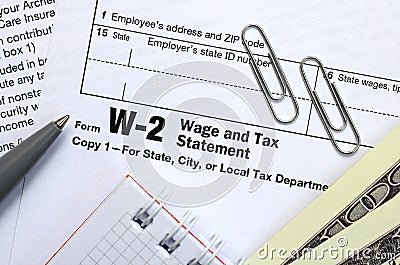 The pen, notebook and dollar bills is lies on the tax form W-2 Wage and Tax Statement. The time to pay taxes Editorial Stock Photo
