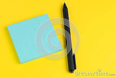Pen with tack of sticky notes on solid yellow background with pink, yellow and blue on top with copy space for writing message Stock Photo