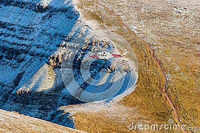 PEN-Y-FAN, WALES - DECEMBER 12 2022: HM Coastguard Search and Rescue helicopter operating above a snow capped Pen-y-Fan in the Editorial Stock Photo