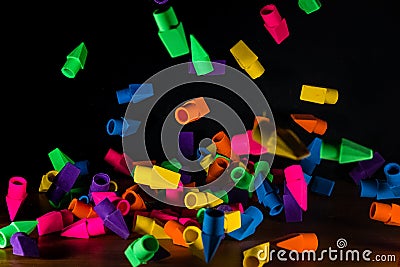 Pencil erasers caught in mid fall cascading onto a wooden deskt Stock Photo