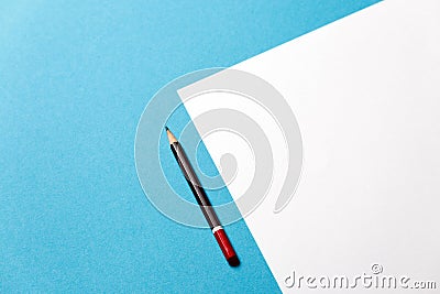 Pencil lies on a paper sheet on blue background, top view. Office space creativity minimalism concept Stock Photo