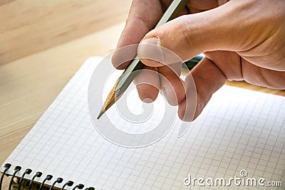 Pencil in male hand and clear sheet of notebook Stock Photo