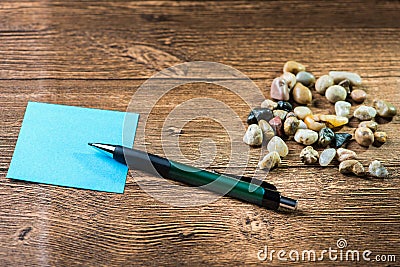 Pencil placed on post-it with many pebbles Stock Photo