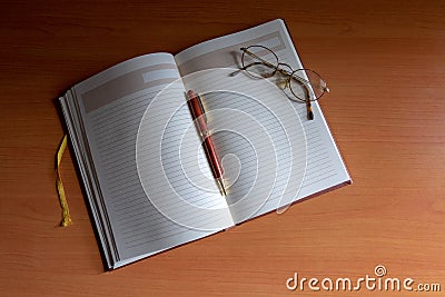 Pencil and reading glasses on a blank journal from above Stock Photo