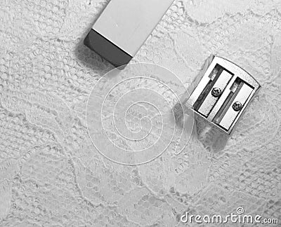 A pencil sharpener and an eraser lies on white lace surface Stock Photo