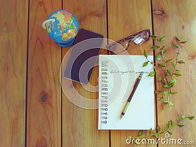 Pencil on white notebook, glasses, phone and globe on wooden floor Stock Photo