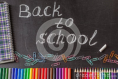 Pencils, clips, notebook and the title Back to school written by white chalk on the black school chalkboard Stock Photo