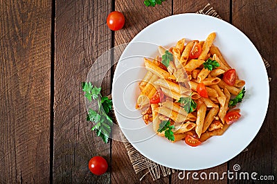 Penne pasta in tomato sauce with chicken, tomatoes decorated with parsley Stock Photo