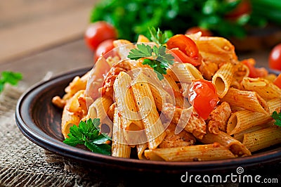 Penne pasta in tomato sauce with chicken, tomatoes decorated with parsley Stock Photo