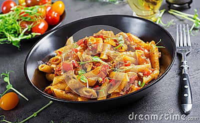 Penne pasta in tomato sauce with meat, tomatoes decorated with pea sprouts Stock Photo