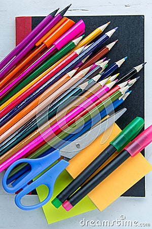 Pens, pencils, scissors and post it notes on black note book Stock Photo