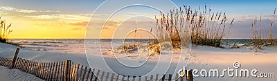 Panoramic photo of a beautiful sunrise at Pensacola Beach Florida with sea oats dunes, and a board fence Stock Photo