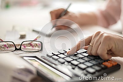 Pension calculation concept, old hands counting finances on a home calculator , close- up Stock Photo