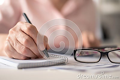 Pension calculation concept, old hands counting finances on a home calculator , close- up Stock Photo