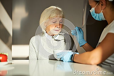 Pensioner having food given by a volunteer Stock Photo