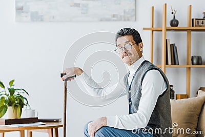 Pensioner holding walking cane and sitting Stock Photo