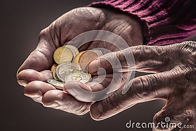 Pensioner man holding in hands euro coins. Theme of low pensions Stock Photo