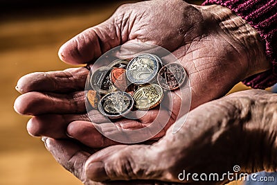 Pensioner man holding in hands euro coins. Theme of low pensions Stock Photo