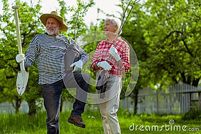 Pensioners caring trees and shovel before planting them near cottage house Stock Photo