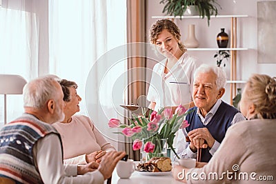 pensioners at retirement home talking during an afternoon snack Stock Photo