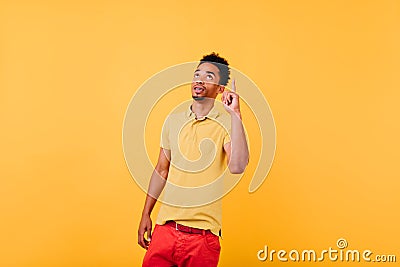 Pensive african model has an idea. Indoor shot of serious black man posing with finger up. Stock Photo