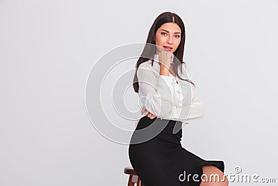 Pensive attractive businesswoman sits on wooden chair Stock Photo