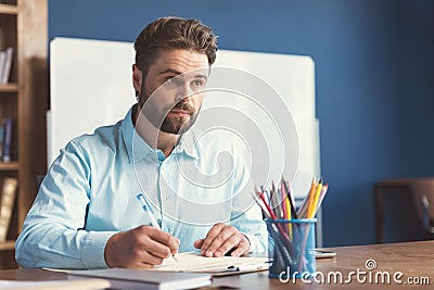 Pensive bearded youthful guy doing employment test indoor Stock Photo