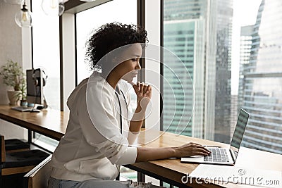 Pensive biracial woman work on laptop in office Stock Photo