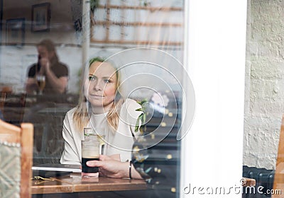 Pensive blonde attractive young adult single woman in pub Stock Photo