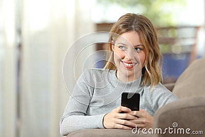 Pensive blonde using a smart phone at home Stock Photo